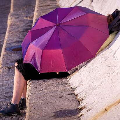 Сочи Згадочная девушка под зонтиком на пляже Сочи. По видимому загорает.